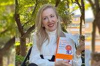 La profesora Victoria de Andrés posa en el Jardín Botánico de la UMA con el libro y la cadera de la austrolopiteca Lucy